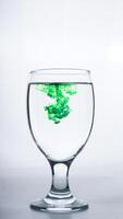 Glass with green colored water isolated on white background photo
