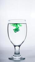 Drinking glass with green colored water isolated on white background photo