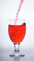 Red colored water poured into transparent glass isolated on white background photo