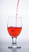 Red colored water poured into glass isolated on white background photo