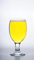 Yellow colored water in drinking glass isolated on white background photo