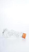 Crumpled plastic bottle waste with orange bottle cap isolated on white background photo