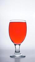 Red colored water in drinking glass isolated on white background photo