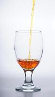 Orange colored water poured into drinking glass isolated on white background photo