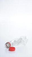 Empty crumpled plastic bottle waste with red bottle cap isolated on white background photo