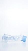Crumpled plastic bottle waste with blue bottle cap isolated on white background photo