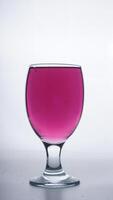 Purple colored water in drinking glass isolated on white background photo