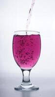Purple colored water poured into transparent glass isolated on white background photo