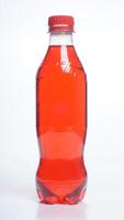 Orange colored water in plastic bottle with red bottle cap isolated on white background photo