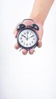 Hand holding classic design of black alarm clock isolated on white background photo