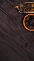 Muslim decoration with islamic lantern and dates fruit for Ramadan and Eid al-Fitr on black fabric background photo