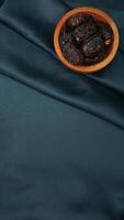 Muslim decoration with dates fruit for Ramadan and Eid al-Fitr isolated on dark green fabric background photo