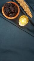 Muslim decoration with dates fruit and islamic lantern for Ramadan and Eid al-Fitr isolated on dark green fabric background photo