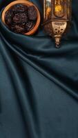 Muslim decoration with dates fruit and Islamic lantern for Eid al-Fitr and Ramadan isolated on dark green fabric background photo
