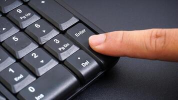 Close up on finger pressing enter key on computer keyboard isolated on black background photo