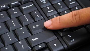 Close up on finger texting on a computer keyboard isolated on black background photo