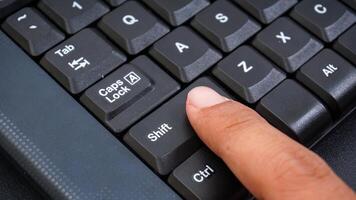 Close up on finger pressing shift button on a computer keyboard isolated on black background photo