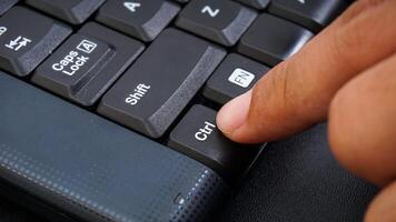 Close up on finger pressing ctrl or control button on a computer keyboard isolated on black background photo