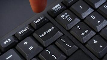 Close up of finger on computer keyboard isolated on black background photo