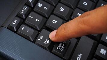 Close up on finger pressing tab button on keyboard isolated on black background photo
