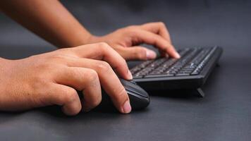 Man hand typing on computer keyboard and holding computer mouse isolated on black background photo