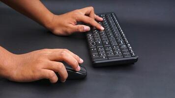 Man hand on computer mouse and typing on keyboard isolated on black background photo