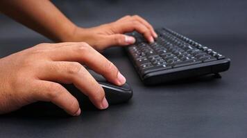 Man hand holding computer mouse and typing on keyboard isolated on black background photo