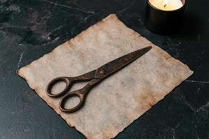 Vintage scissors on parchment paper with a candle photo