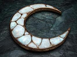 Crescent moon pendant with opal gemstones and gold setting on a dark textured surface photo
