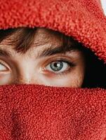 Close up of a persons face with freckles and green eyes, partially covered by a red towel photo