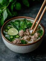 A bowl of Vietnamese pho with beef, noodles, and fresh herbs photo