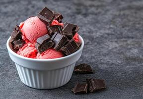 A bowl of strawberry ice cream with dark chocolate chunks photo