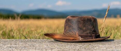 A brown hat with a feather sits on a stone surface in a field photo