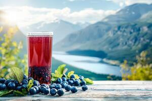 Glass of red juice is on a table with a bunch of blueberries photo