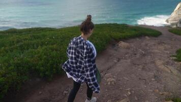 A young woman is happily exploring a beautiful scenic coastal path, enjoying nature video