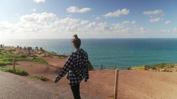 A woman gracefully walking by the beautiful coast, enjoying the scenic view of the ocean video