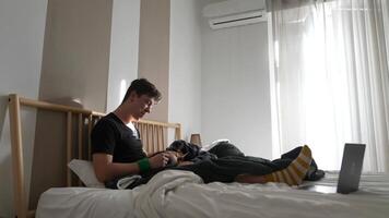 A Young Man Enjoying a Relaxing Time in His Bed while Using a Laptop and a Phone video