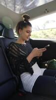 A young woman engaged and focused on her smartphone while sitting in the backseat of a car video