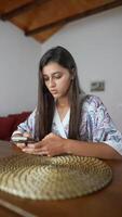 A focused young woman deeply engaging with her mobile device in a serene and comfortable setting video