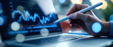 hand using stylus on laptop displaying market graph photo