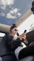 A Young Woman Engaged with Her Smartphone While Relaxing Inside a Car, Capturing the Urban Vibe video