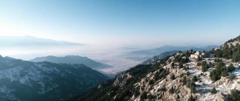building on a snowy mountaintop overlooking a vast valley under a clear sky photo