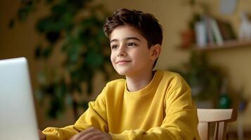 A young boy sitting at a desk in his room focused on his laptop as he studies or completes homework online photo