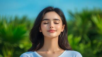 A woman with her eyes closed in a moment of tranquility immersed in the calming presence of nature and the fresh outdoor air around her photo