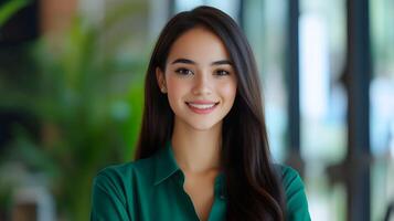 A friendly and confident young woman dressed in a green shirt poses with a warm smile in her professional workplace setting photo