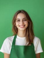 Cheerful portrait of a young attractive woman wearing a green apron and smiling brightly against a vibrant green background photo