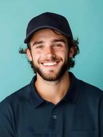 Friendly and approachable portrait of a young man with a beard wearing a black cap and casual attire smiling confidently against a vibrant colored background photo