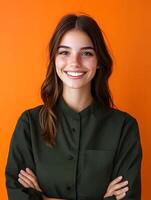 Cheerful portrait of a young woman likely a professional hair stylist with a warm friendly smile and confident expression set against a vibrant orange background photo