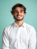 Friendly and approachable young man in a white shirt smiling confidently against a blue background representing a helpful and personable reservationist or customer service professional photo