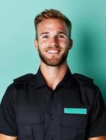 Portrait of a young friendly and confident individual wearing a black uniform and smiling at the against a vibrant turquoise background photo